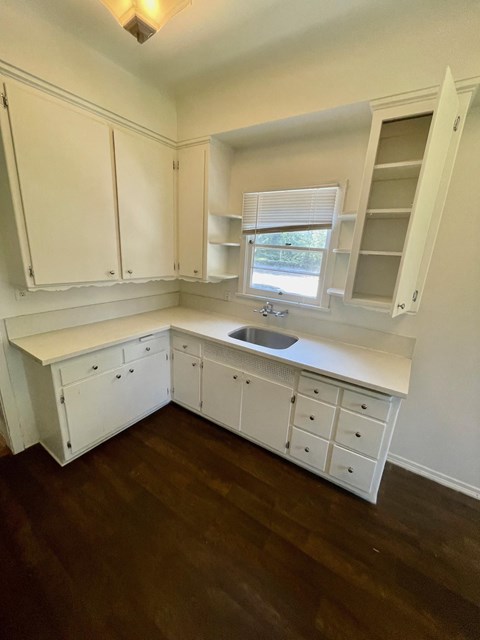 a kitchen with white cabinets and a sink and a window